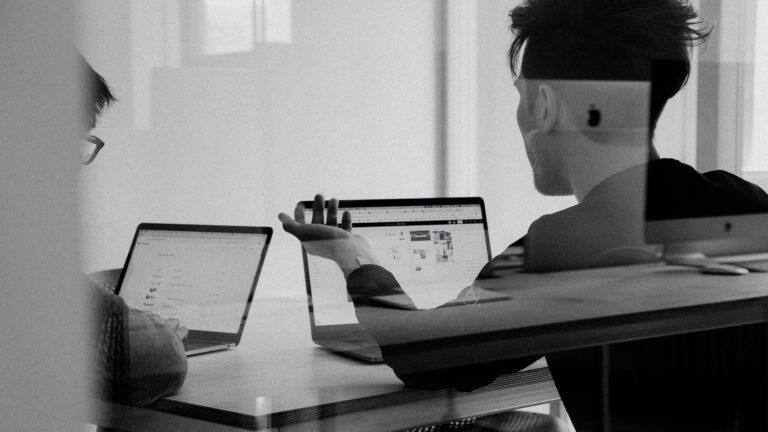 Two people having a conversation in front of their laptops