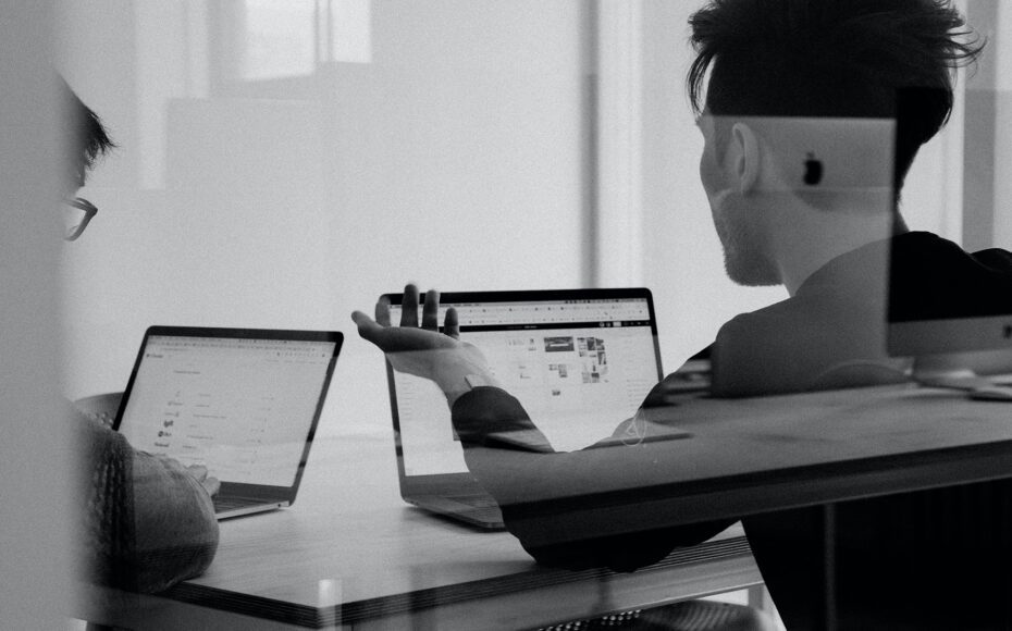 Two people having a conversation in front of their laptops